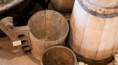 Zdjęcie przedstawia dawne drewniane przedmioty używane przy przerobie mleka i są to: maselnica i dwa czerpaki.